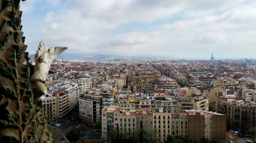 High angle view of city buildings against cloudy sky