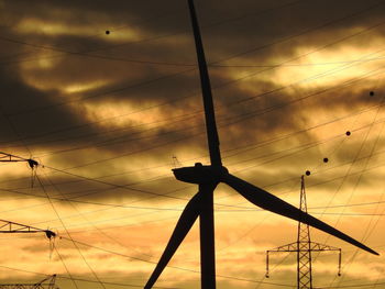 Low angle view of silhouette electricity pylon against sky during sunset