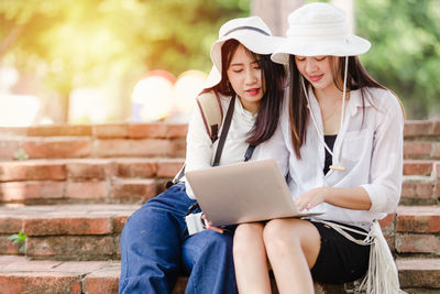 Midsection of woman using mobile phone while sitting outdoors