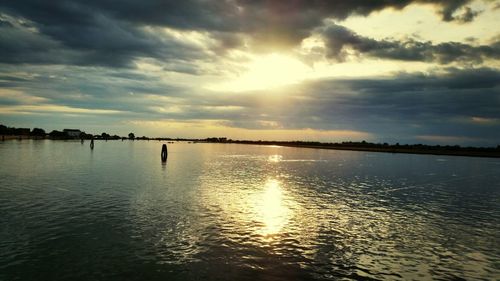 Scenic view of sea against cloudy sky at sunset