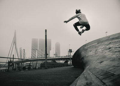 Man skateboarding in city against clear sky
