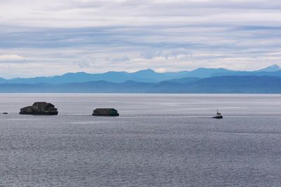 House on tugboat in sea against cloudy sky