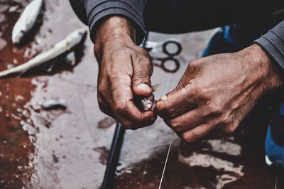 Cropped hands of man removing fish from hook