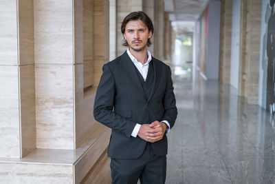 Portrait of businessman standing against wall