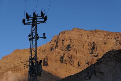 Low angle view of electricity pylon against mountain 