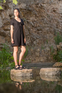 Portrait of young woman standing on rock