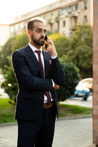 Young businessman talking on mobile phone on footpath