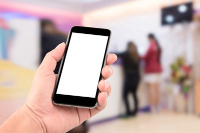 Cropped hand holding blank mobile phone in shopping mall
