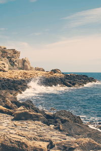 Rock formation on beach against sky