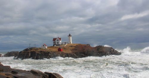 Lighthouse by sea against sky