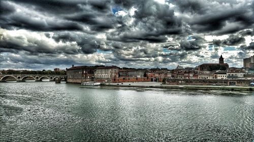 River in city against cloudy sky