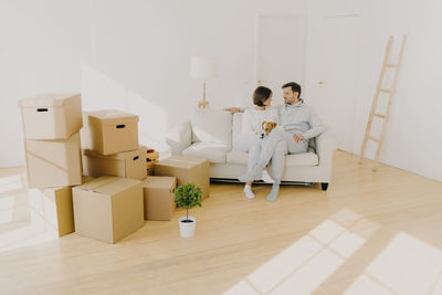 Couple with dog sitting on sofa in new home