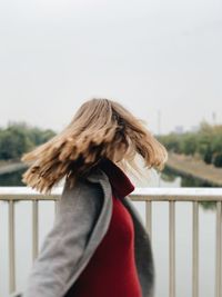 Midsection of woman standing by railing against sky