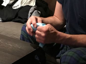 Midsection of man holding while sitting at home