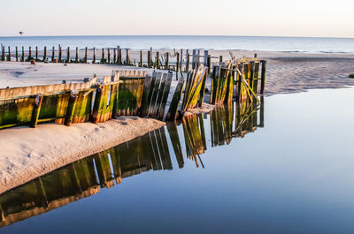 Wooden posts in sea against clear sky