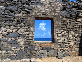 Stone wall by sea against sky