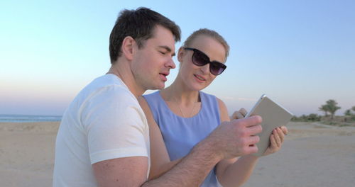 Friends enjoying on beach against sky