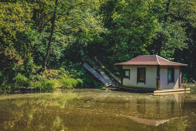 House by lake amidst trees in forest