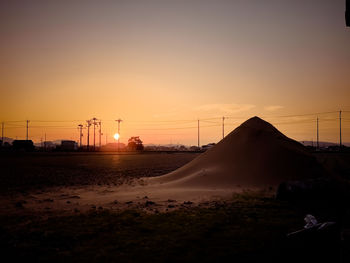 Silhouette electricity pylon against sky during sunset