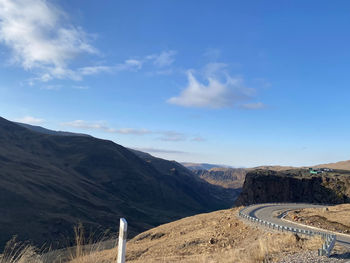 Road leading towards mountains against blue sky