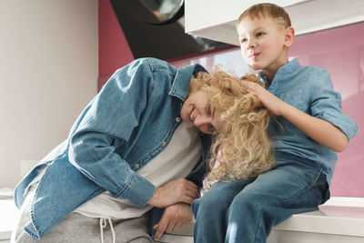 Portrait of boy with teddy bear while sitting on sofa at home