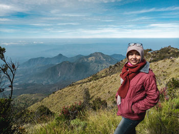 Portrait of smiling woman standing on mountain against sky