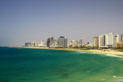 Sea by city against clear sky