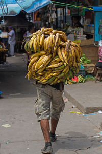 Rear view of man eating food at market stall in city