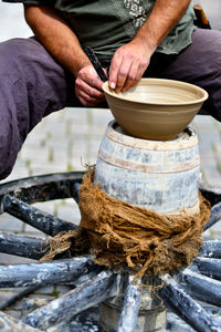 Midsection of man making clay pot