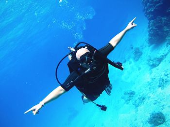 Man with arms outstretched scuba diving in sea