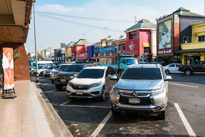 Cars on city street by buildings against sky