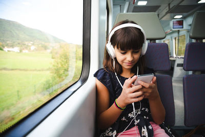 Young man using mobile phone while standing by window