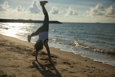 Woman doing handstand at beach