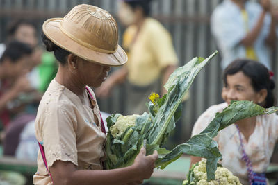 Side view of woman carrying cauliflower at market