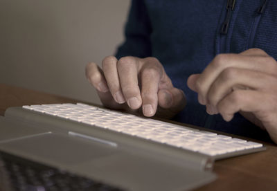 Midsection of man typing on keyboard at table