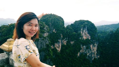 Portrait of woman smiling while gesturing against mountains