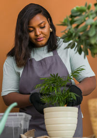 Portrait of young woman holding potted plant