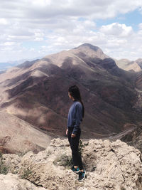 Rear view of man standing on mountain against sky