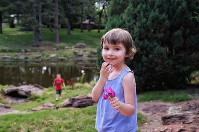 Portrait of girl holding pink flowers while standing on field