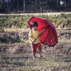 Full length of woman holding umbrella on field