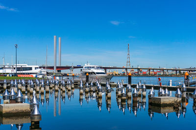 Boats moored at harbor against blue sky