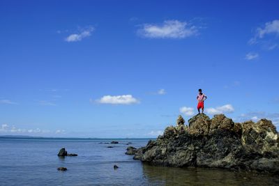 Boy standing by sea on rock