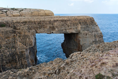 Rock formations by sea against sky