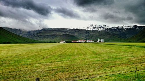 Scenic view of grassy field against cloudy sky