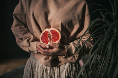 Midsection of woman holding strawberry
