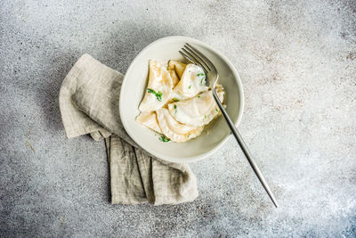 From above traditional ukrainian dumplings stuffed with potato, well-known vareniki, served in a bowl with sour cream