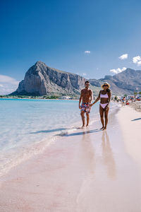 Women walking on beach by sea against sky