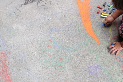 Cropped hands of child drawing on street