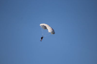 Low angle view of person paragliding against clear blue sky