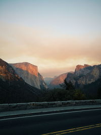 Road by mountains against sky during sunset